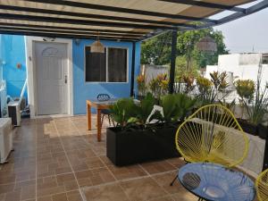 um pátio com cadeiras, uma mesa e uma parede azul em Guest house La Casa del Quetzal em Mérida