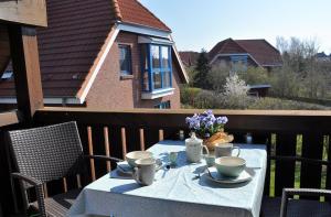 a table with cups and saucers on a balcony at Ort Lemkenhafen Ostseeperle in Fehmarn