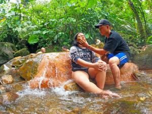 a man and a woman sitting on rocks in a stream at Termales el Escondite in Florencia