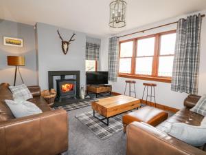 a living room with leather furniture and a fireplace at Clearwater House in Lochailort