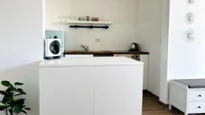a white kitchen with a microwave on top of a counter at APARTELLO Modern Apartment - Garden of Eden in Sveti Vlas