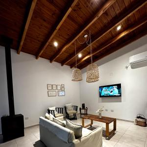 una sala de estar con paredes blancas y techos de madera. en Quinta El Hornero en Esperanza