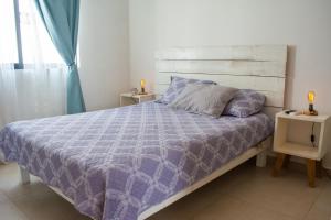 - un lit avec une couette violette dans une chambre dans l'établissement Paraíso Playa Bonita- Roof Top, à Playa del Carmen