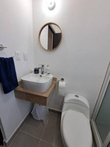 ein Badezimmer mit Toilette, Waschbecken und Spiegel in der Unterkunft Casa, alberca, club de playa WI-FI en Acapulco in Barra Vieja