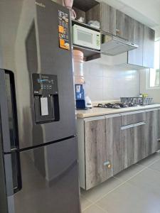 eine Küche mit einem Kühlschrank aus Edelstahl und einer Mikrowelle in der Unterkunft Casa, alberca, club de playa WI-FI en Acapulco in Barra Vieja