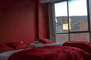 ラパスにあるLobo Hostel La Pazのベッド2台 赤い部屋 窓付