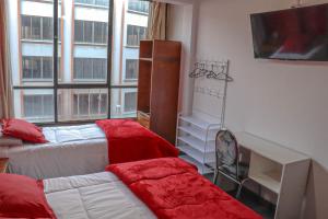 ラパスにあるLobo Hostel La Pazのベッド、デスク、窓が備わる客室です。