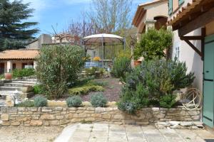 a garden with a stone wall and a gazebo at Villa Sénégas in La Roque-sur-Cèze