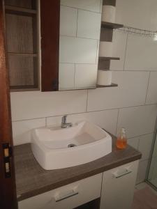 lavabo blanco en el baño con espejo en Conforto e comodidade em Santa Maria, en Santa Maria