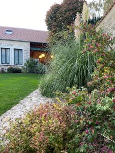 a garden with flowers and plants in front of a house at La Planque - Chambres avec Jacuzzi in Fleury-en-Bière