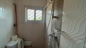 a bathroom with a toilet and a window at RÉSIDENCE MEUBLÉE 1ERE CLASSE DOUALA pk 15 in Douala