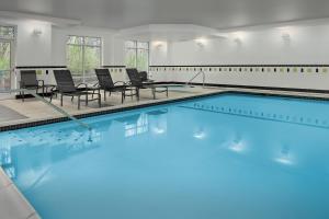una grande piscina con sedie e tavoli in un edificio di Fairfield by Marriott Tacoma Puyallup a Puyallup