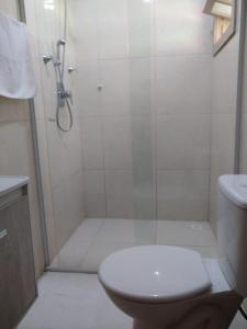 a white bathroom with a shower and a toilet at Espaço Rural Sítio Do Sol in Guabiruba