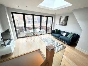 uma sala de estar com um sofá azul e uma mesa de vidro em London Duplex Apartment 2 bedroom with Terrace em Londres