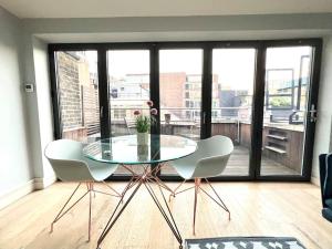 a glass table and two chairs in a room with a balcony at London Duplex Apartment 2 bedroom with Terrace in London