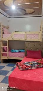 Ce lit superposé se trouve dans un dortoir doté d'un couvre-lit rouge. dans l'établissement Repos Surf House 1, à Sidi Ifni