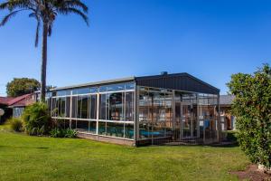 une maison en verre avec une piscine et un palmier dans l'établissement Arkana Motor Inn & Terrace Apartments, à Mount Gambier