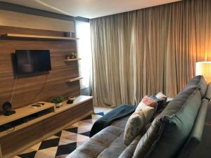 uma sala de estar com um sofá e uma televisão em Apartamento La Vista em Gramado