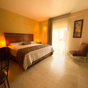 a bedroom with a bed and a chair and a window at Hotel Quinta Roca in Oaxaca City +5 photos