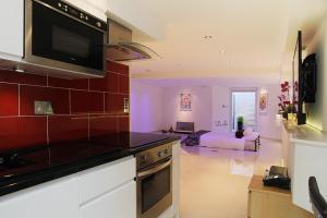 a kitchen with a stove top oven next to a living room at Holiday Lets London in London