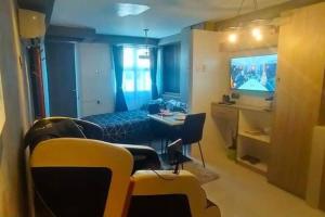 a room with a table and chairs and a television at Blk Pod 