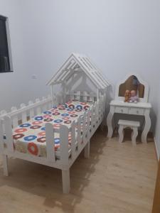 ein Schlafzimmer mit einem weißen Kinderbett, einem Bett und einem Tisch in der Unterkunft Casa grande em arapongas in Arapongas