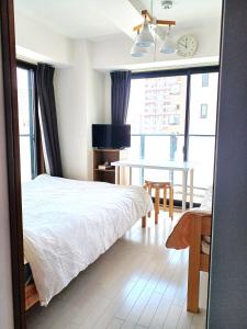 1 dormitorio con cama, mesa y ventana en オリエントシティ南堀江Ⅱ, en Osaka