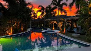 a large swimming pool with a sunset in the background at Alona Royal Palm Resort in Panglao