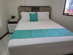 伊塔佩馬的住宿－Apartamento vista mar com 3 quartos e churrasqueira，一间卧室配有一张带蓝白色枕头的大床