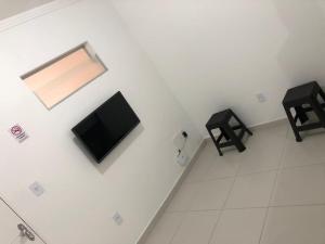 um quarto com uma televisão numa parede com dois bancos em Apt05-06-07 no centro,a 800mts do pátio do forró em Caruaru