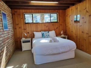 a bedroom with a white bed in a wooden wall at Sunbakers in Forster