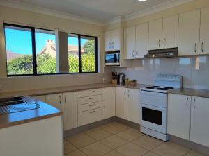 eine Küche mit weißen Schränken und einem großen Fenster in der Unterkunft Sunbakers in Forster