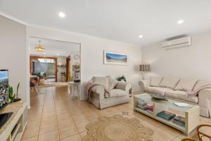 a living room with two couches and a table at Crowford Sands by Experience Jervis Bay in Sanctuary Point