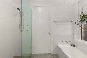 a white bathroom with a shower and a bath tub at Crowford Sands in Sanctuary Point +11 photos