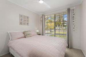 a white bedroom with a bed and a window at Crowford Sands by Experience Jervis Bay in Sanctuary Point