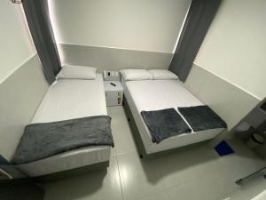 2 Betten befinden sich in einem kleinen Zimmer mit in der Unterkunft Suíte com banheiro privativo em Pousada recém construída,a 500mts do pátio do forró in Caruaru
