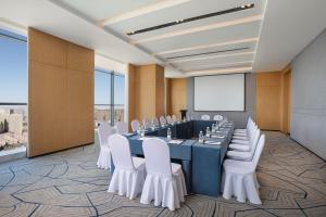 Fairfield by Marriott Shijiazhuang High-Tech Zone في هيبي: قاعة اجتماعات مع طاولة طويلة وكراسي بيضاء