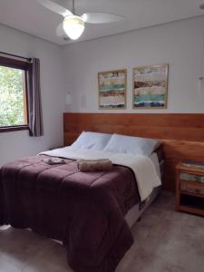 a bedroom with a large bed with a brown blanket at Vila Verde Chalés-Serro in Sêrro