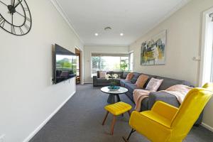 a living room with a couch and a clock on the wall at Doncaster Renovated 5BD/4BR Brick Home Parking WiFi in Doncaster
