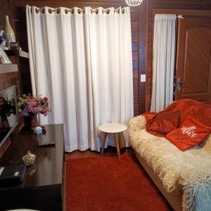 ein Wohnzimmer mit einem weißen Vorhang und einem Sofa in der Unterkunft Chalés Alto do Capivari in Campos do Jordão