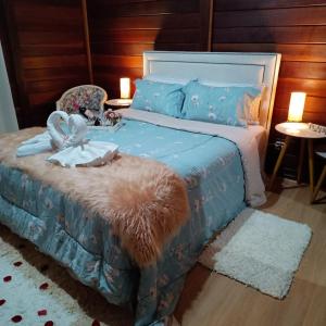 een slaapkamer met een bed met een blauw dekbed en een stoel bij Chalés Alto do Capivari in Campos do Jordão