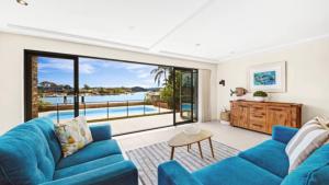 a living room with a blue couch and a view of the water at Tranquil Lagoon - Waterfront Luxury in Daleys Point