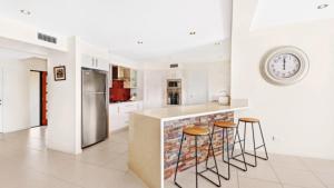 a kitchen with a counter with stools and a clock on the wall at Tranquil Lagoon - Waterfront Luxury in Daleys Point