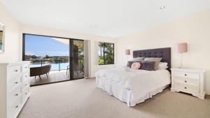 a white bedroom with a bed and a balcony at Tranquil Lagoon - Waterfront Luxury in Daleys Point +7 photos