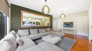 a living room with a white couch and a tv at Beach Shack - Waterfront Patonga in Patonga