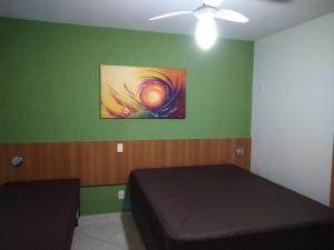 ein Schlafzimmer mit einem Bett und einem Gemälde an der Wand in der Unterkunft 1406 AP 2 Quartos Shopping, Banheira de Hidro privativa , bebidas liberadas nas piscinas e internet no ap, proximo ao shopping singapura in Caldas Novas + 50 Fotos