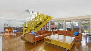 a living room with a couch and a yellow staircase at Sand & Sea Pearl Beach Family Fun in Pearl Beach