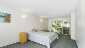 a white bedroom with a bed and a window at Sand & Sea Pearl Beach Family Fun in Pearl Beach