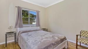 Patonga BeachにあるPatonga Sunset - Waterfront Holiday Houseのベッドルーム1室(ベッド1台、窓、椅子付) +7枚の写真