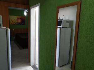 ein Raum mit einer grünen Wand mit einem Kühlschrank und einer Mikrowelle in der Unterkunft 1406 AP 2 Quartos Shopping, Banheira de Hidro privativa , bebidas liberadas nas piscinas e internet no ap, proximo ao shopping singapura in Caldas Novas